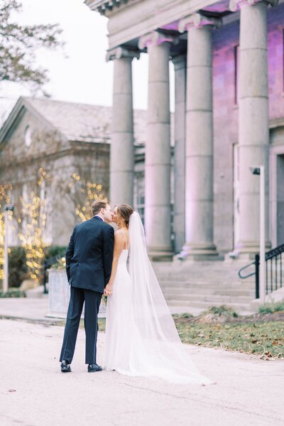 Bride and groom kiss in front of historic building