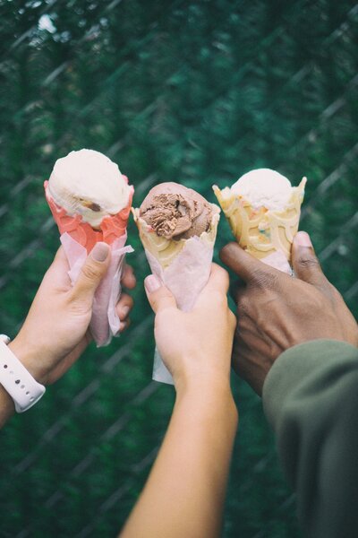 Three hands holding ice cream cones.