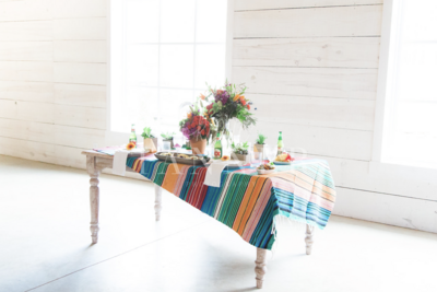 table decorated with colorful cloth and florals and colorful fruit