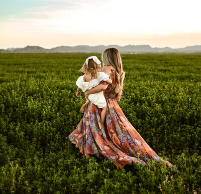 mom walking with daughter in green field