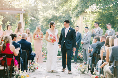 bride and groom looking at each other as they walk down the aisle leaving their wedding ceremony at lady bird johnson wildflower center wedding venue