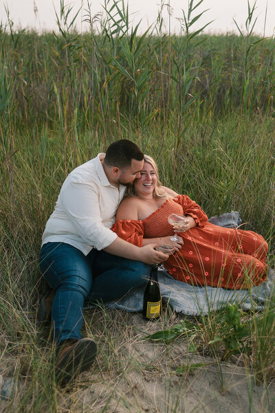 Couple sitting in grass with champagne