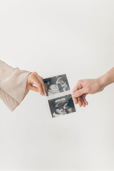 Close-up image of two hands holding an ultrasound photo together in anticipation of their Kansas City baby.