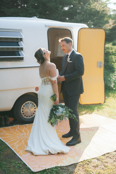 bride and groom laugh next to their Boler camper