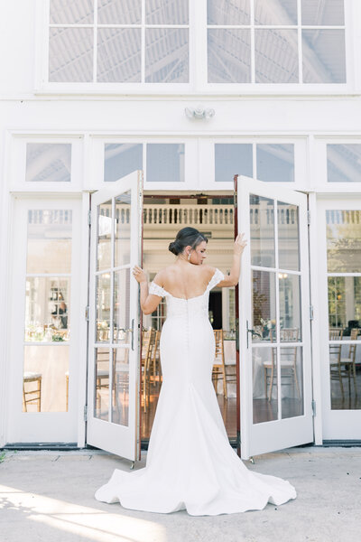 Bride standing in the doorway of Raspberry Plains Manor, captured in a romantic and timeless moment on her wedding day.
