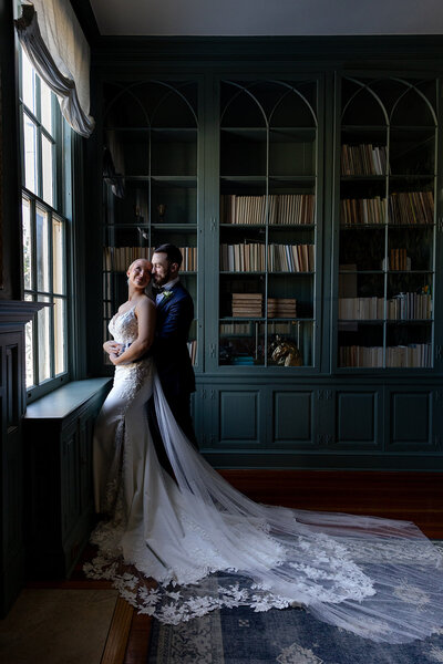 bride and groom holding each other by window