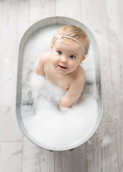 one year old in bubble bath as part of a cake smash session