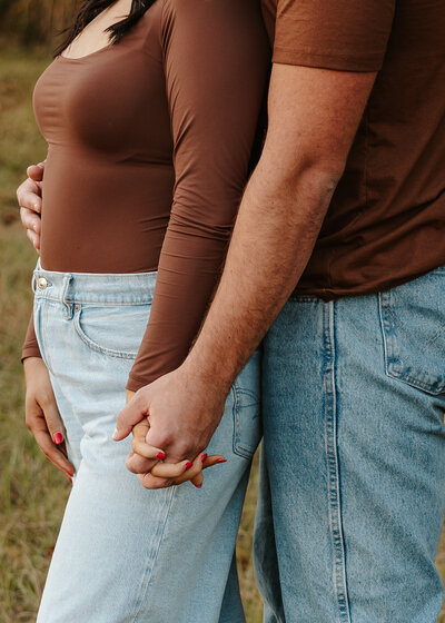 Couple holding hands during a fall photoshoot in a a golden farm field in Aiken South Carolina, photographed by KateLens Photography.
