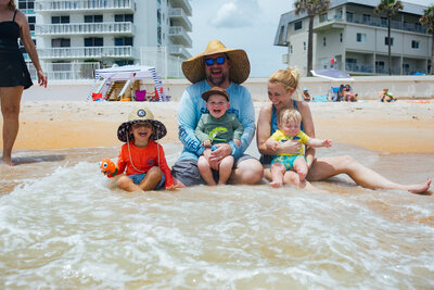 Family of five on the beach getting splashed with waves