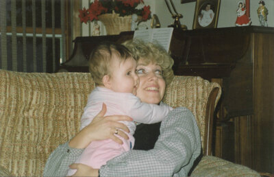 a mom holding her baby on a couch in the 1980s.