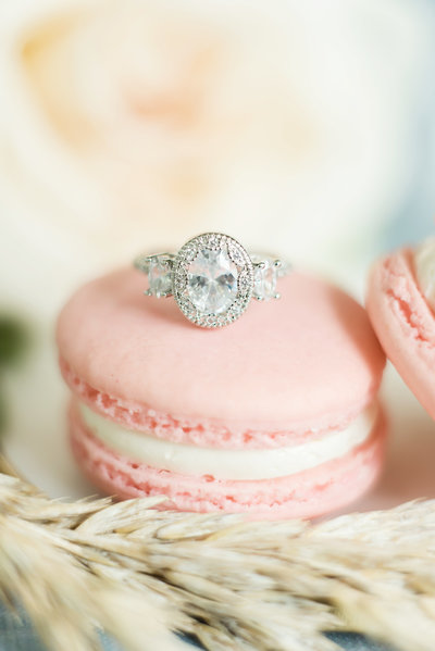 Beautiful wedding ring sits atop a pink macaron