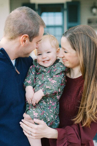 mom and dad snuggling their little girl