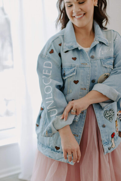 Woman with dark hair in jean jacket and pink skirt