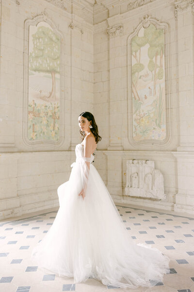 Candid image of a bride in long flowing white wedding dress in the halls of Chateau Jalesnes