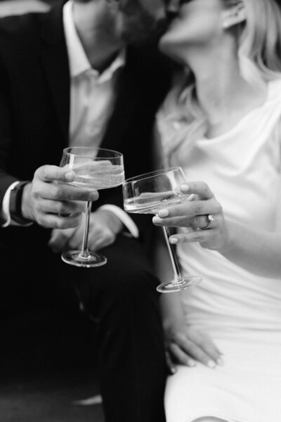couple clinking glasses while kissing in the background