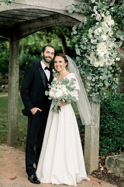 Wedding Day couple  posing next to wedding florals in Dunwoody Georgia