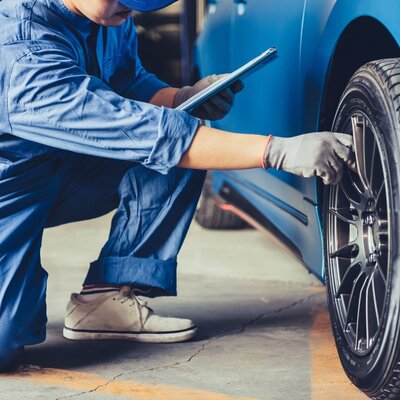 A faceless mechanic is shown working on a tire, representing Ecosystem's commercial trash service for a variety of businesses.