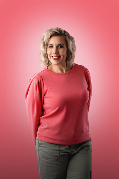 Photographer Michelle Gritters stands in her pink studio in a pink top