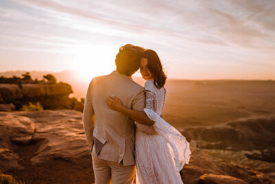 bride and groom hug at sunset