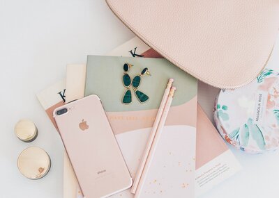 flatlay of a pink and grey notebook on a table next to a pink iphone and two pencils