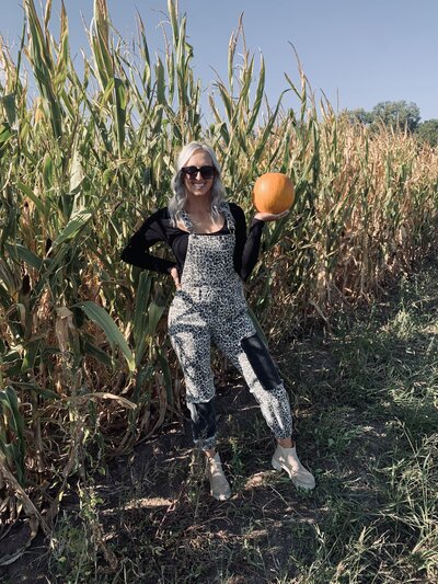 girl holding a pumpkin near crops