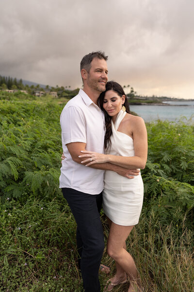 Maui Family Photographers capture couple hugging while man looks at water during Maui family photos