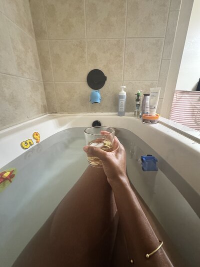 Black career coach for professional women drinking wine in the tub