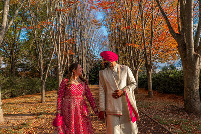 A newlywed couple holding hands and walking together in a park 