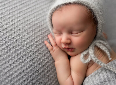 A sleeping newborn boy in grey. Photo by Diane Owen.