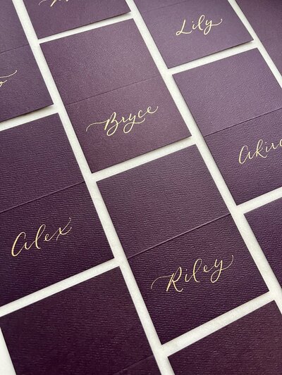 Aubergine place cards with gold ink calligraphy