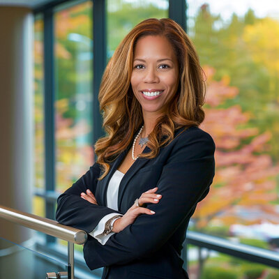 Professional headshot of businesswoman in blazer smiling warmly outdoors with fall foliage background new jersey.