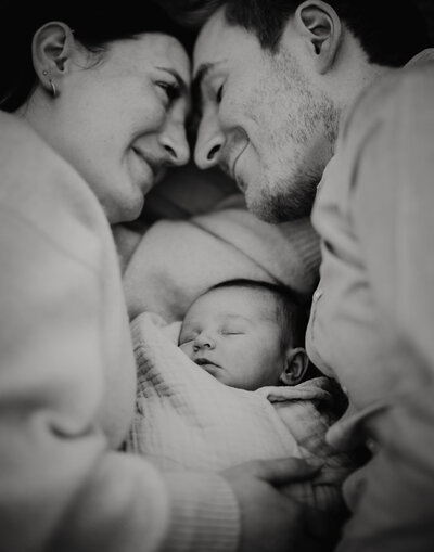 Couple on a picnic rug with their newborn asleep between them