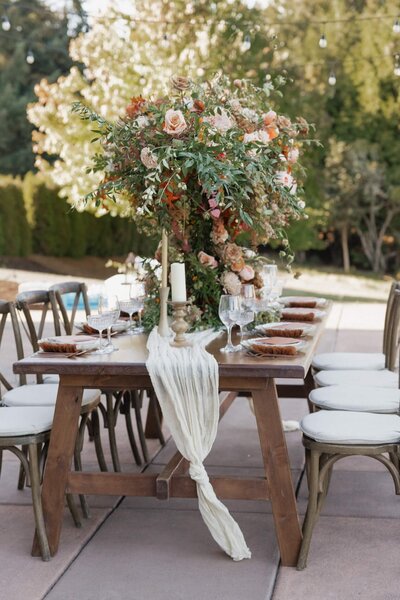A farmhouse table with a large floral arrangement and place settings, representing wedding design inspiration for planning. 