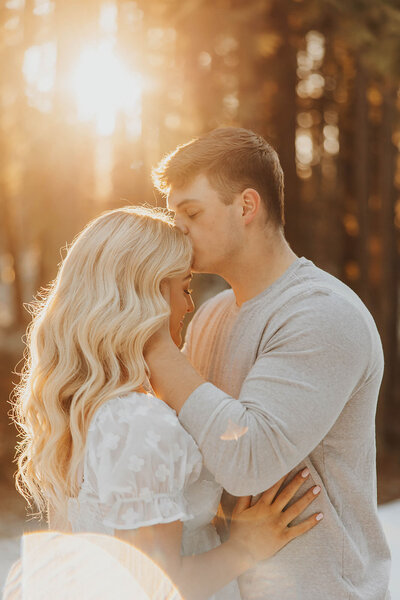 Man kissing his partner’s forehead during golden hour in a Montana field.