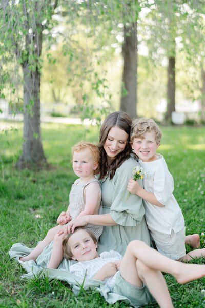 a-mom-of-three-boys-is-smiling-at-one-of-her-boys-and-the-boys-are-smiling-back-at-thecamera-for-family-photos-with-nashville-family-photographer-dolly-delong-photography