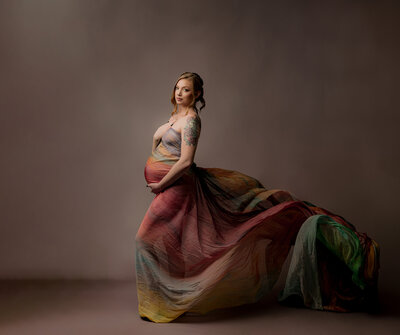 new Mother holding pregnant belly while son with blonde hair and blue eyes pokes her belly button