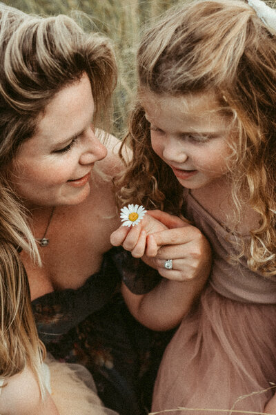 Toddler girl shows her mother a daisy she found. 