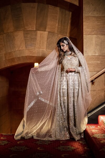 Indian Bride holding out veil in front of steps.
