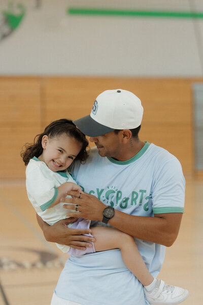 coahc holding a little girl smiling