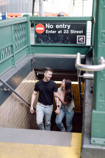 Engaged couple walking up the stairs from a New York City subway station during their NYC engagement session.