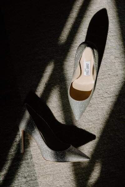 Shadows cast over a pair of heels on the ground 