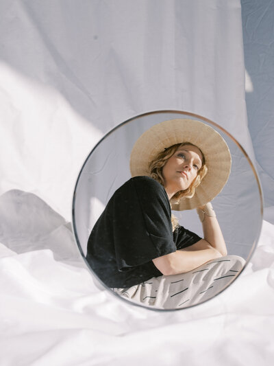 Renee Swigert, owner  of Arc Design Haus, is reflected in a round mirror  as she  sits in the sun.  | Arc Design Haus | Pittsburgh Brand Photographer | Anna Laero Photography