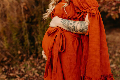 Pregnant mother in orange dress during outdoor maternity photoshoot in Cleveland TX