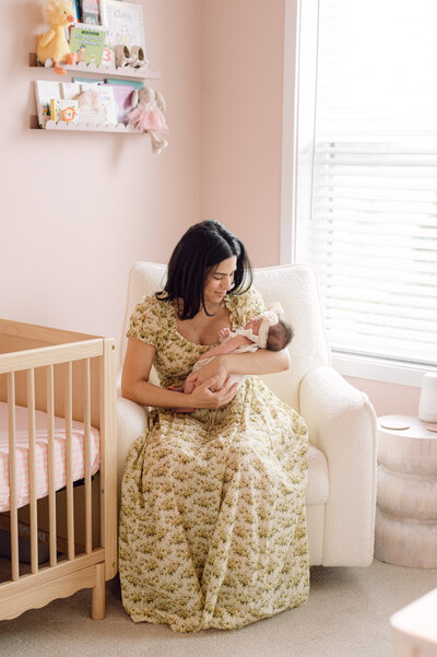 A mother sits in the nursery holding her newborn baby during a lifestyle session photographed by a Richmond Virginia family photographer.
