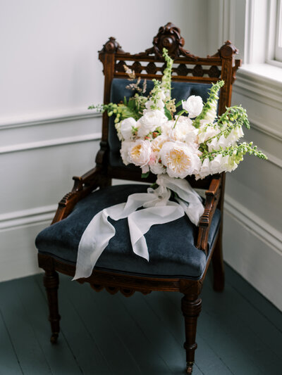 A vintage chair with a hue of light pink flowers by Colorado Wedding Photographer JKG Photography