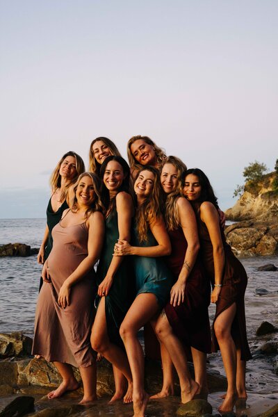 A group photo of women in the Full Spectrum Woman Membership on a rocky beach