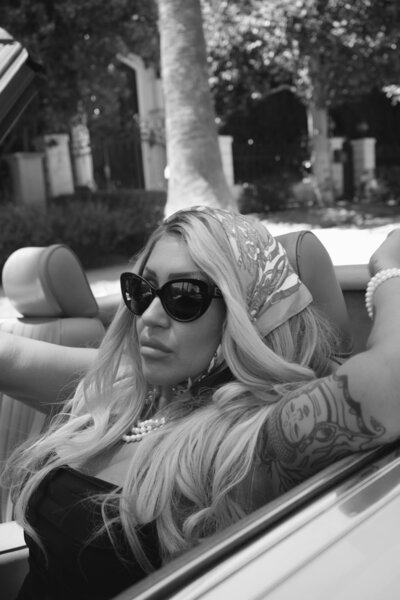 Nicky Lynn standing near a convertible by the coast, representing a bold new chapter and personal freedom