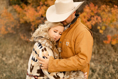 A woman resting her head lovingly on her husbands chest during Montana's fall season.