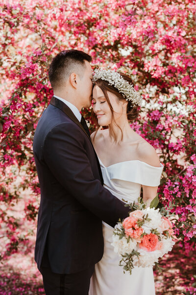 Wedding couple standing in front of cherry blossom trees in Boston, MA