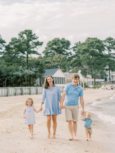 Family of four holding hands and walking on beach during their photo session with a Southern Maryland Phographer.